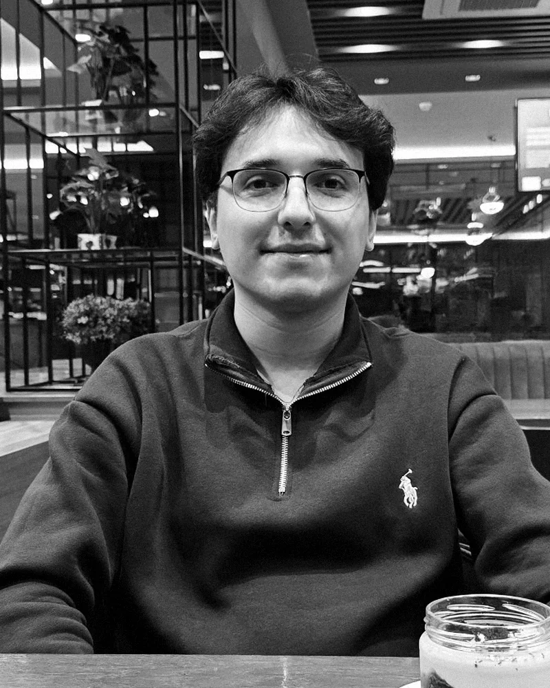 Batuhan Kaş sitting at a table in a café.